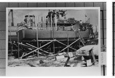 Boat being constructed with several men on deck working.