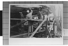Two men working underneath an unknown ship