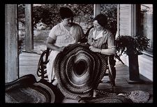 Women displaying braided rug. Black and white photo. 