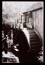 Man beside a water wheel. Black and white photo. 