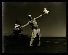 Landing signalman bringing in plane  