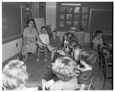 Children and Teacher Sitting on Chairs in a Semi-circle 