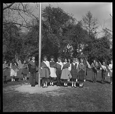 Students Wearing Sashes and Carrying U.S. Flags around a flagpole