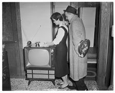 A man surprises a woman with a Valentine over a TV