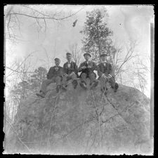 Four men sitting on a cliff or a huge rock