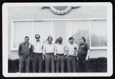 Building with Pepsi cap logo sign, six men in front